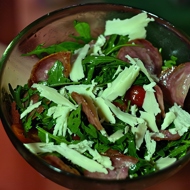 Теплый салат с руколой, помидорами черри, жареными колбасками сальчичон и пармезаном