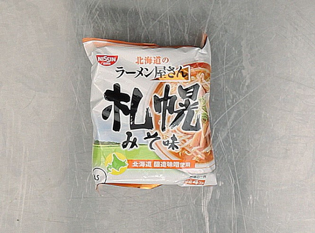 Лапша «Саппоро-мисо», сделана той самой пищевой японской корпорацией Nissin, которую создал Момофуку Андо. В состав действительно входит мисо — помимо заменителя сахара, неуточненных специй и приправ, лактозы, лука, гидролизатора белка, углекислого натрия, карбоната кальция, красителя, загустителя и витамина E. По идее, эту лапшу, как написано на пачке, нужно варить 3 минуты в кипящей воде, а потом добавлять все остальное — может, потому что мы ее заваривали, она и не произвела ни на кого особого впечатления.